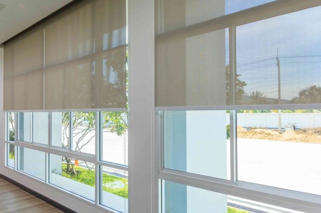 Sunscreen blinds installed in wall-to-ceiling glass windows.