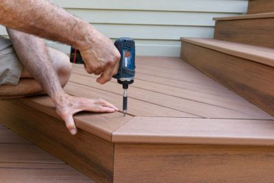 Close-up of worker using drill to install new porch decking